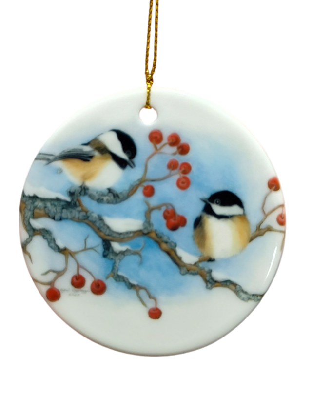 The Ornament: Winter Chickadees Ceramic Ornament features two chickadees on snowy branches with red berries, accented by a gold hanging string—a delightful bird-themed Christmas decoration for your tree.