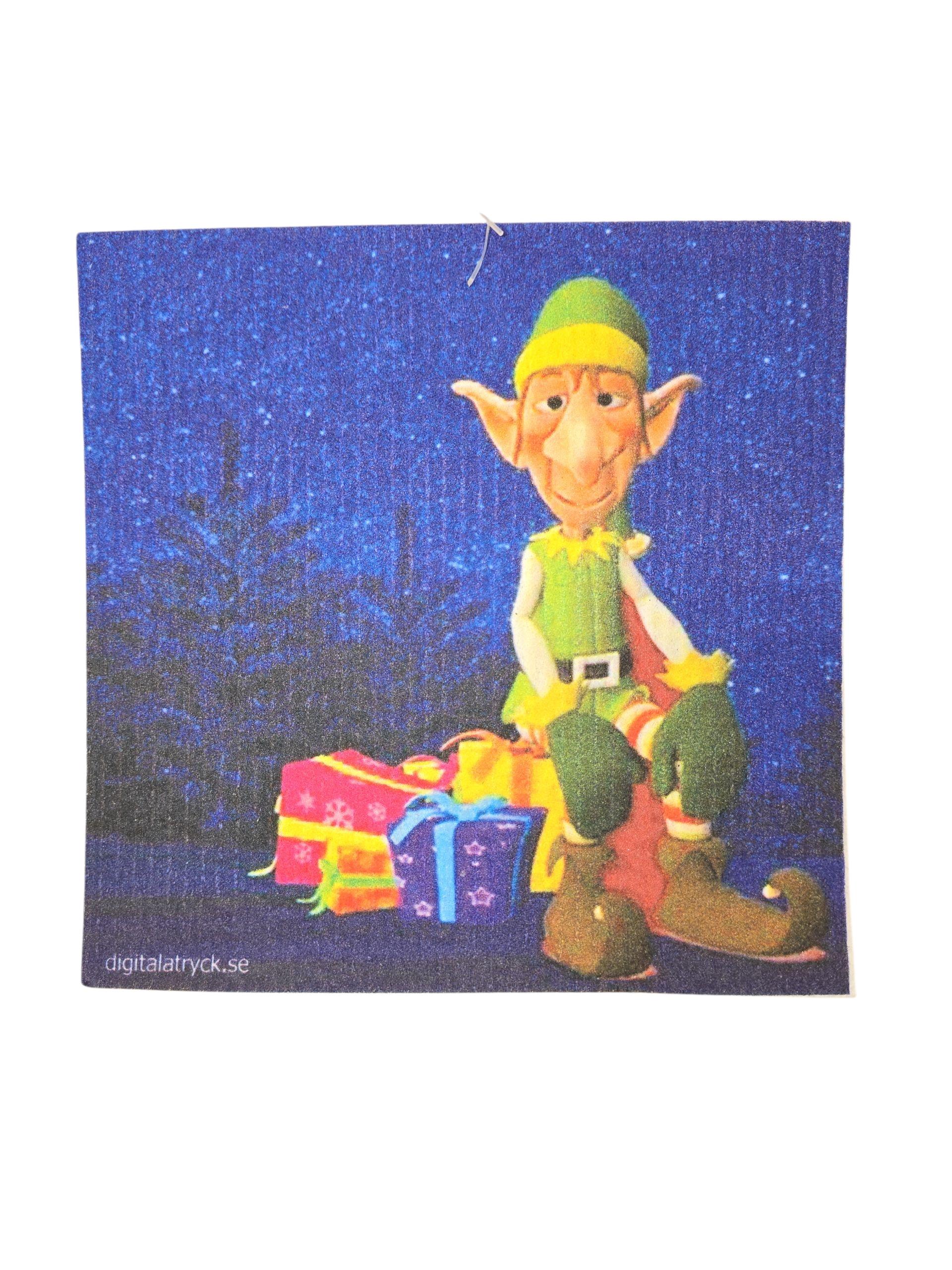 Illustration of an elf sitting on presents beside a festive Swedish dish cloth, set against a blue, starry background—perfect for the Christmas season. Product: Dish Cloth: Elf Sitting on Presents Swedish Dish Cloth.