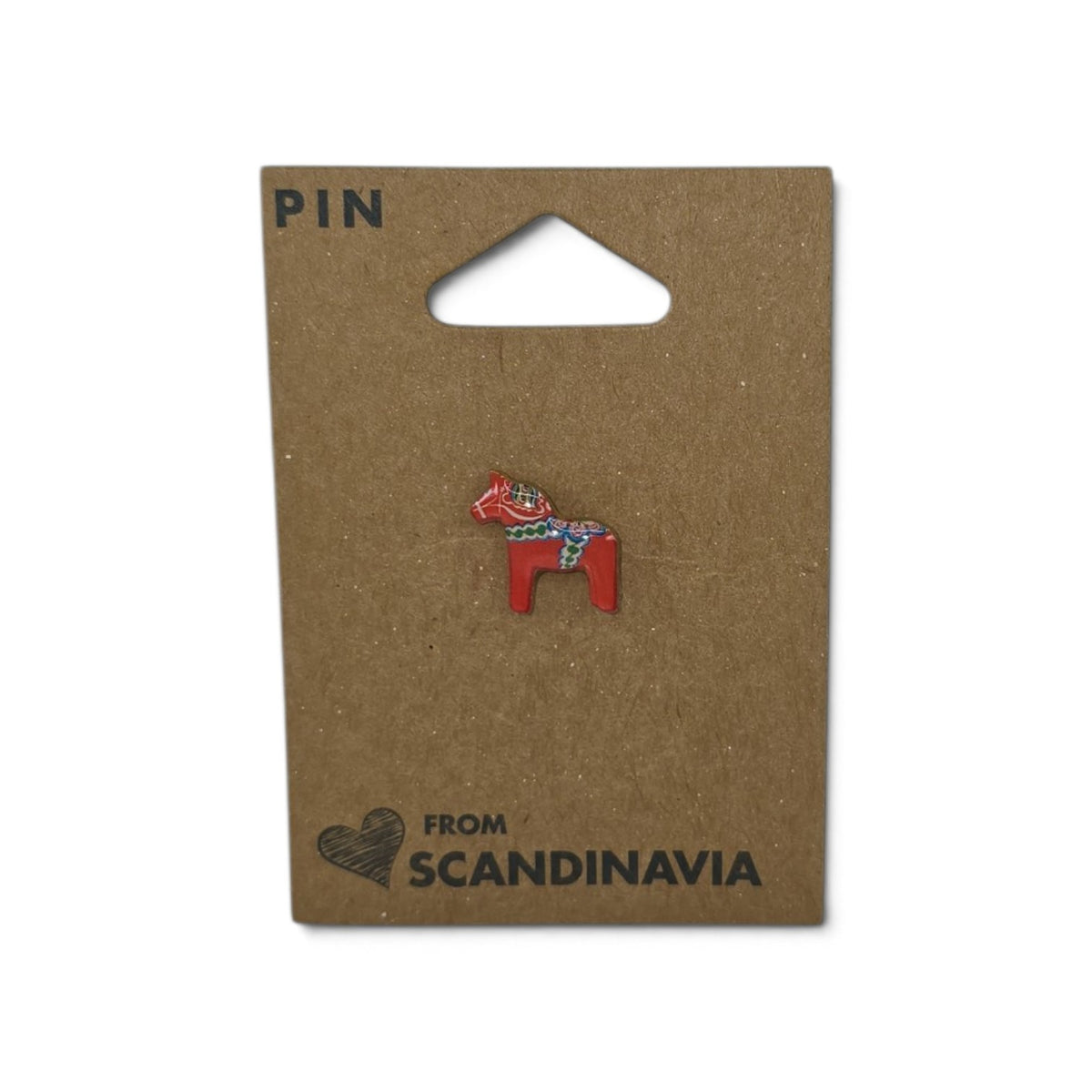 Red Dala horse lapel pin with decorative pattern, attached to brown card labeled “PIN” and “FROM SCANDINAVIA” with a small heart illustration.