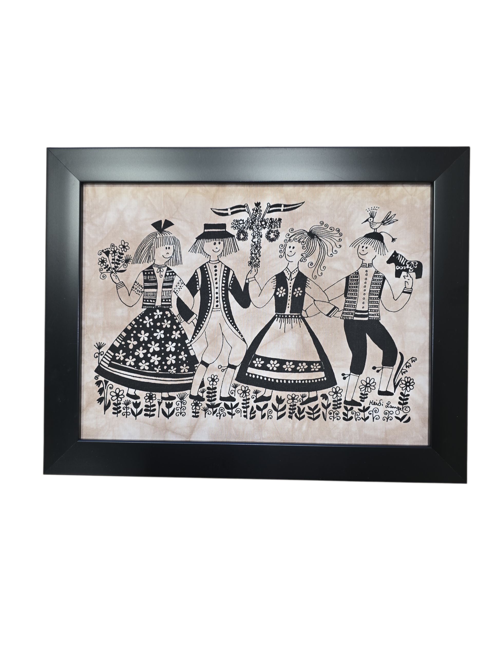 The “Two Swedish Couples Dancing” framed batik artwork by Heidi Lange (11x14, black frame) features four people in traditional Swedish clothing holding hands, inspired by folk art and surrounded by floral patterns.