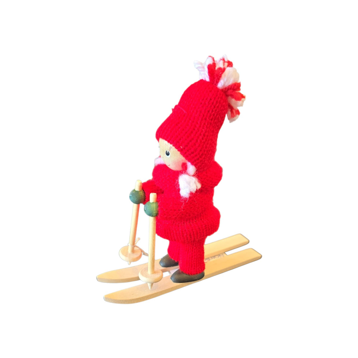 Scandinavian gnome figurine wearing a red knitted outfit and hat, standing on wooden skis and holding poles.