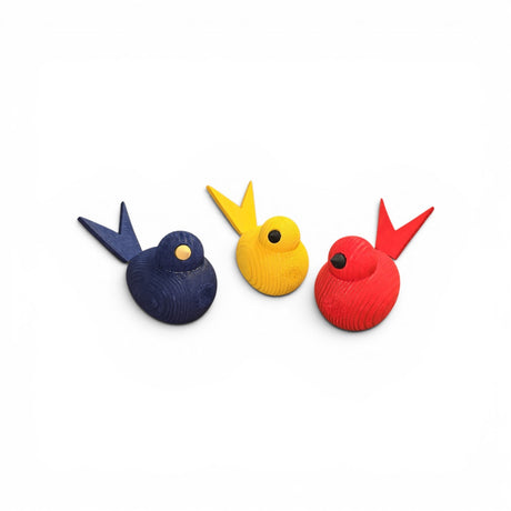 Bergquist Imports’ Wooden Scandi Birds—handcrafted 3" figurines from Sweden—feature blue, yellow, and red finishes with matching tails and round beaks, highlighting Nordic craftsmanship against a plain white background.