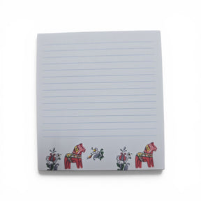 The Swallings Dala Horse Note Pad (3.76"w x 4"h) features blue lines on a white background, with two red Swedish Dala horses and vibrant floral designs at the bottom. Made in Sweden.