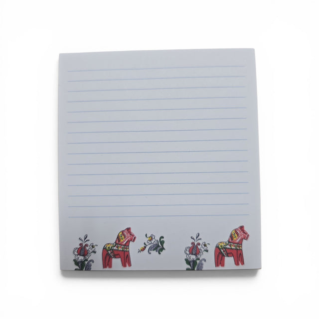 The Swallings Dala Horse Note Pad (3.76"w x 4"h) features blue lines on a white background, with two red Swedish Dala horses and vibrant floral designs at the bottom. Made in Sweden.