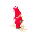 Scandinavian wooden figurine of a skier wearing a red knit hat and suit, holding two ski poles.