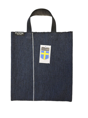 The Horredsmattan Floow Vinyl Bag (32x40cm) is a dark blue tote with black handles, a vertical white stripe, FLOOW. label, Swedish flag tag, and features the iconic Swedish vinyl rug design.
