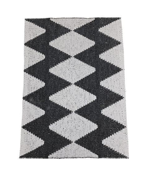The Horredsmattan Zigge vinyl rug features a rectangular design with black and white geometric diamonds and gray stripes on one side; this stylish Swedish rug is durable and machine washable for easy care.