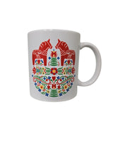 The Swedish Gift Store's 11oz ceramic mug features two red Dala Horses amid colorful Swedish folk flowers and leaves, inspired by Scandinavian design.