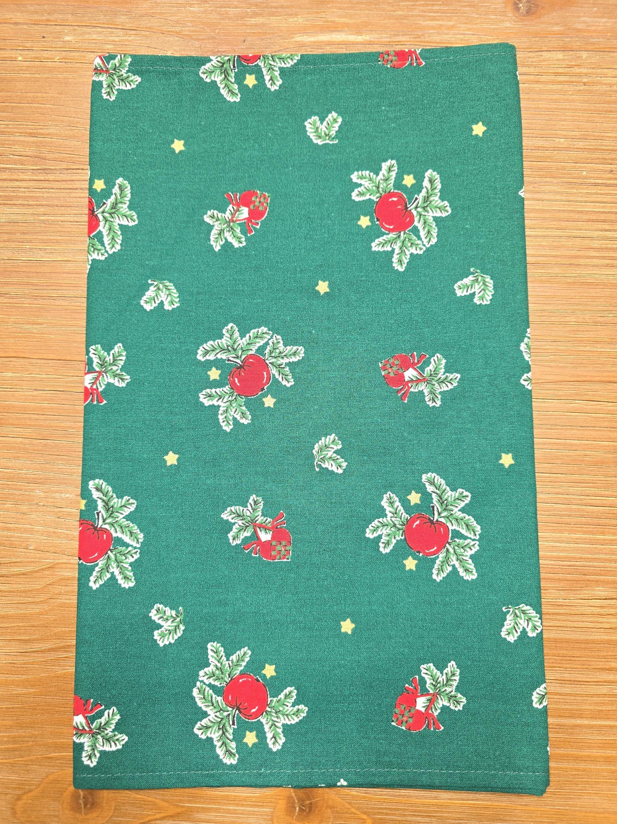 The "Jul Apple" table runner features red apples, green leaves, yellow stars, and woven Danish hearts on apple green cloth—perfect for Swedish Christmas decor. Measures 48" long and looks charming laid flat on your table.