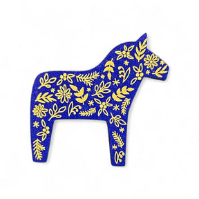 The Magnet: Blue Swedish Dala Horse with Yellow Kurbits Refrigerator Magnet is a charming Minnesota souvenir, handcrafted from wood and featuring traditional yellow kurbits designs on a blue background.