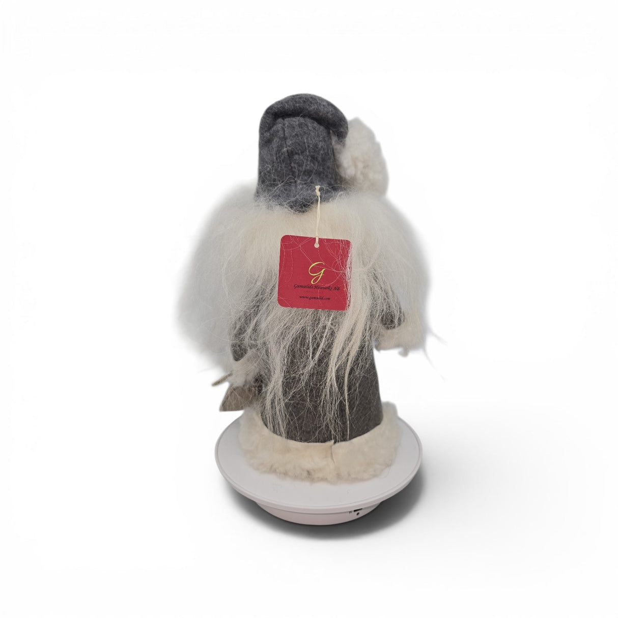 A "Tomte with Robe" and burlap bag gnome figurine by Talla Imports, handcrafted by Gumselids of Sweden, is displayed from the back, standing 12 inches tall on a wooden base. The figure features white hair and beard, wears gray attire, and has a red tag attached to its back. The background is plain white.