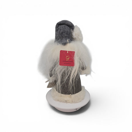 A "Tomte with Robe" and burlap bag gnome figurine by Talla Imports, handcrafted by Gumselids of Sweden, is displayed from the back, standing 12 inches tall on a wooden base. The figure features white hair and beard, wears gray attire, and has a red tag attached to its back. The background is plain white.