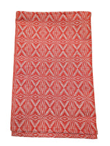 A folded "Norrland" table runner, 48" long, in reddish orange with silver ice star patterns.
