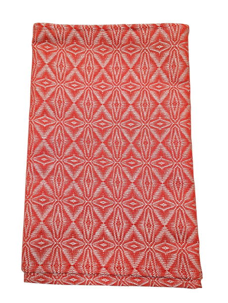 A folded "Norrland" table runner, 48" long, in reddish orange with silver ice star patterns.
