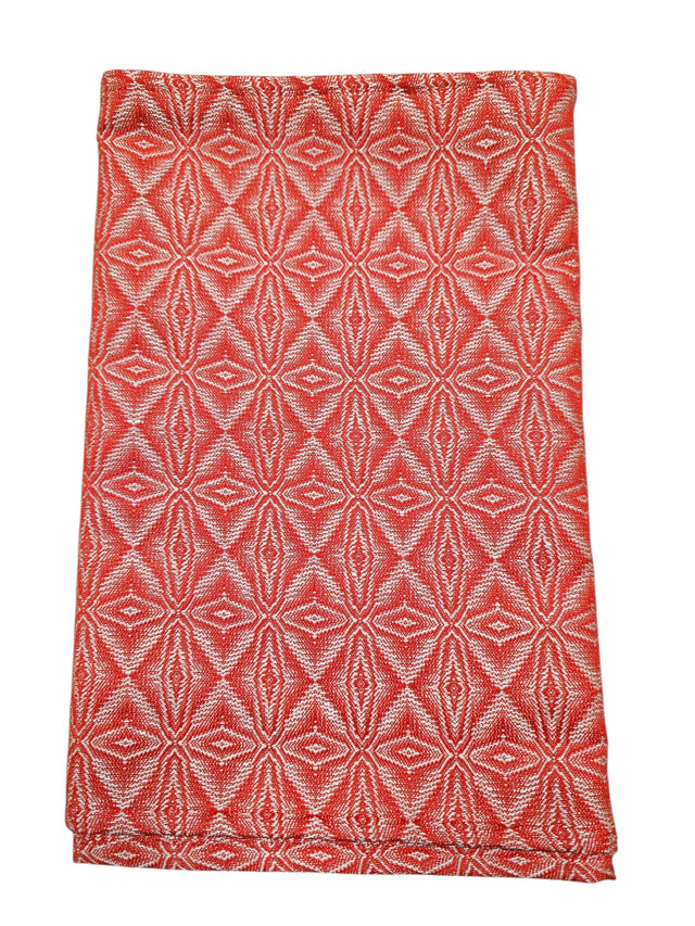 A folded "Norrland" table runner, 48" long, in reddish orange with silver ice star patterns.