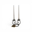 The Talla Imports Danish Iron Double Curls Taper Candle Holder elegantly displays two white taper candles, with a small "DANISH IRON" tag in front, highlighting Scandinavian craftsmanship against a plain white background.