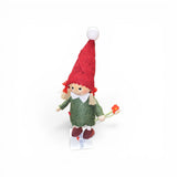 The Figurine: Scandinavian Girl Tomte by Faire - Nordic Dreams is a handcrafted gnome in a green dress and red hat, holding flowers—a charming Scandinavian Christmas decoration.