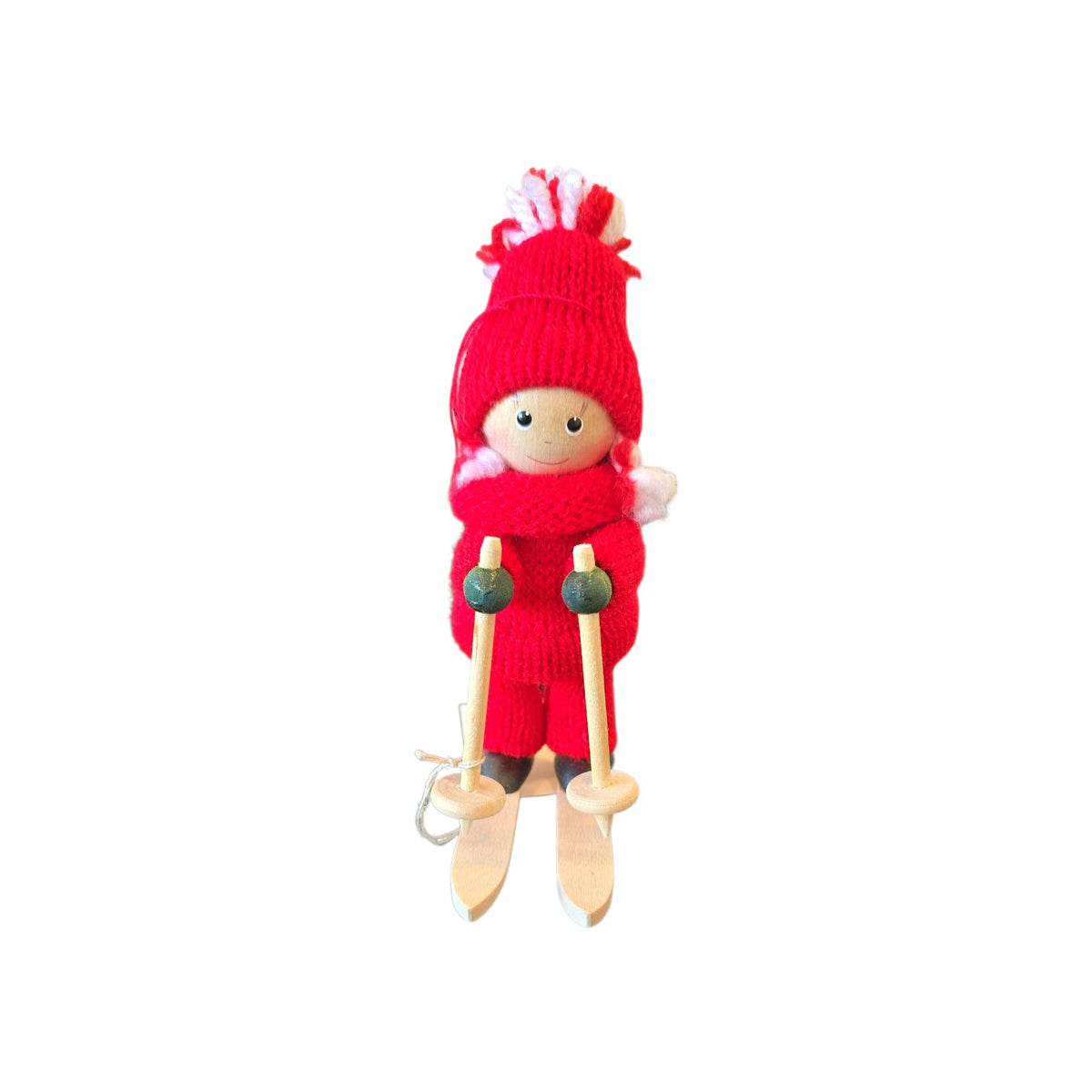 Scandinavian girl figurine wearing a red knit hat and sweater, standing on wooden skis and holding poles.
