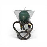A green candle in a Leif Cup for Ball Candle sits on the Talla Imports Danish Iron Candle Holder with Heart, with a product tag behind it and a white background.