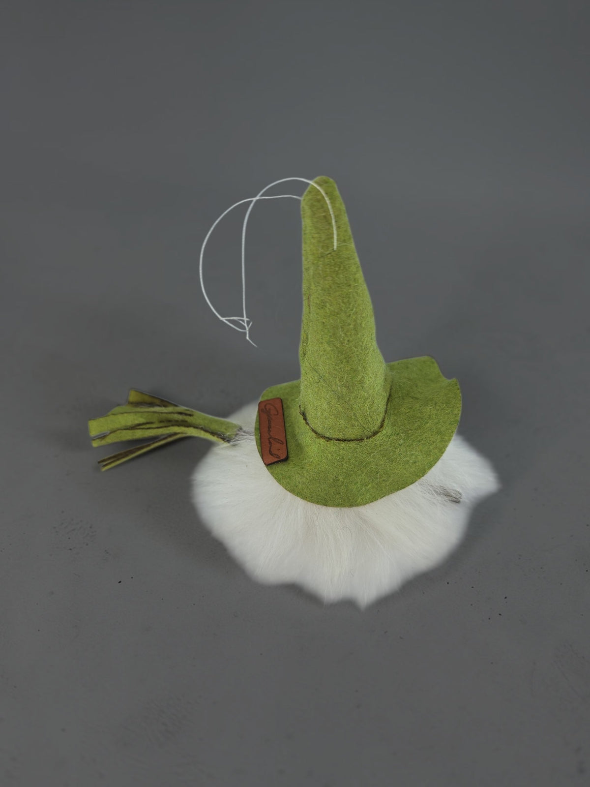 Green felt gnome ornament with a white beard and a hanging string.