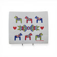 The Dish Cloth: Six Dala Horses with Swedish Kurbits "Flowers" shows six colorful Dala horses, three red hearts, a central floral pattern, and the artist Anna Linderholm's name in the lower right corner.