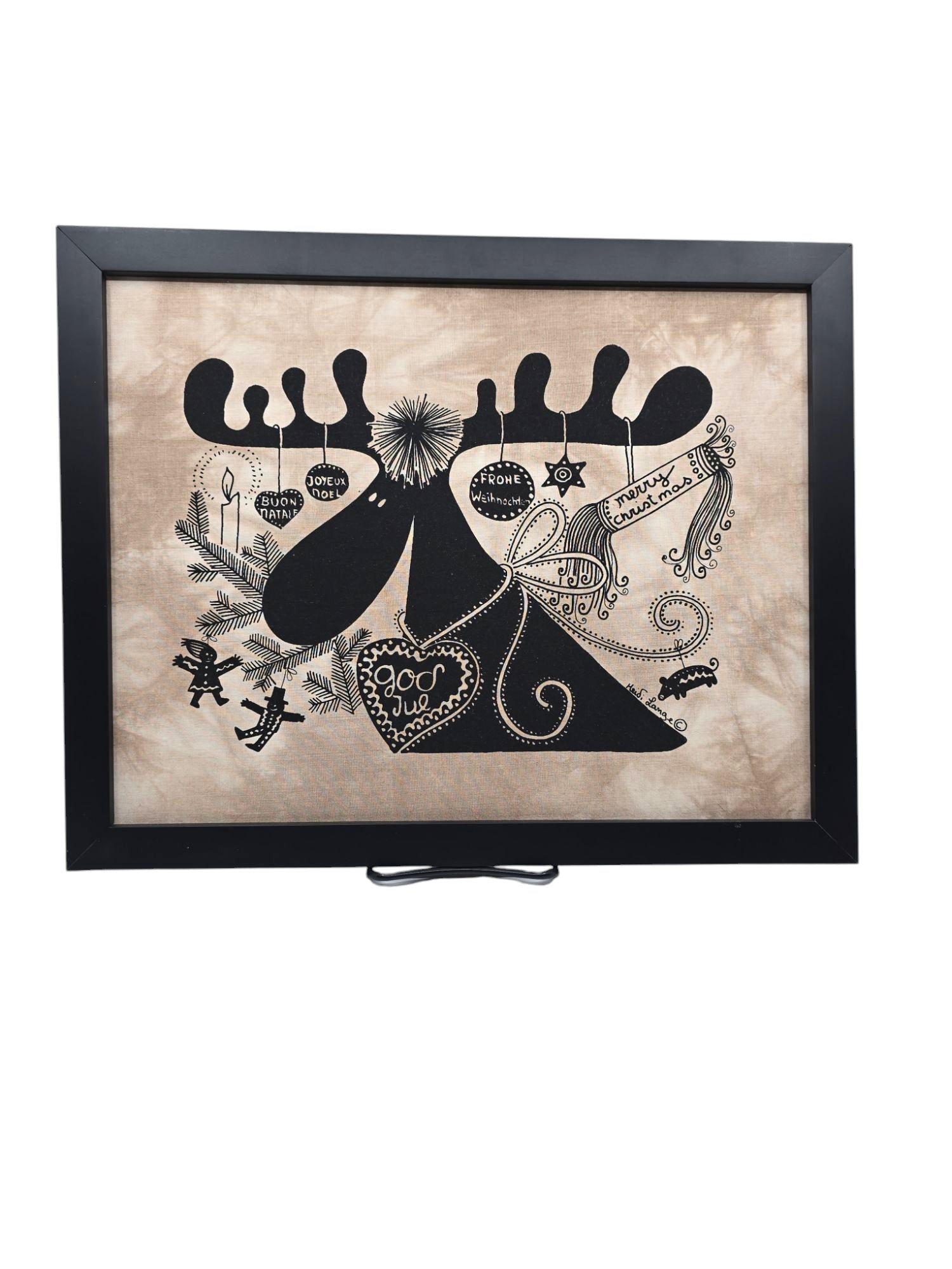 The framed artwork Moose God Jul (14x11) by Heidi Lange features a moose silhouette with ornaments on its antlers, styled with designs reminiscent of her African screen prints.