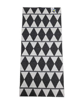 The Vinyl Rug: Horredsmattan - Zigge features a rectangular woven design with a black and white geometric diamond pattern, gray stripes on one side, and a small corner tag.