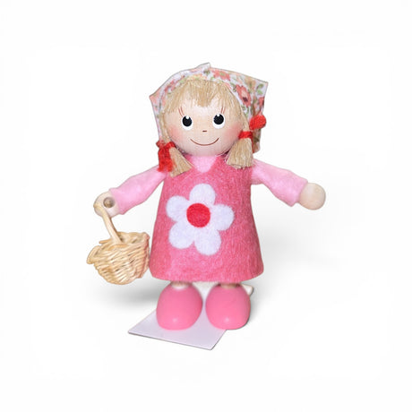 The Figurine: Scandinavian Tomte Girl in Pink by Faire - Nordic Dreams features a charming gnome with blonde hair, a floral headscarf, pink dress and shoes, holding a woven basket—an ideal accent for Nordic-inspired decor. Made in Scandinavia.
