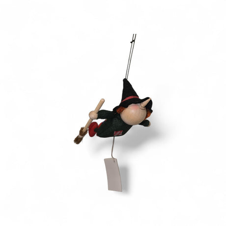 The Kitchen Witch Handcrafted Wood and Felt Figurine, 4.5" long, features a pointed hat, red shoes, and broomstick—suspended by string with a blank tag. A charming Nordic decor piece and traditional household guardian.