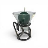 A green round candle in a glass cup sits on the Talla Imports Danish Iron Candle Holder with Heart & 1 Leif Cup, a handmade decor piece featuring a heart design, displayed against a white background.