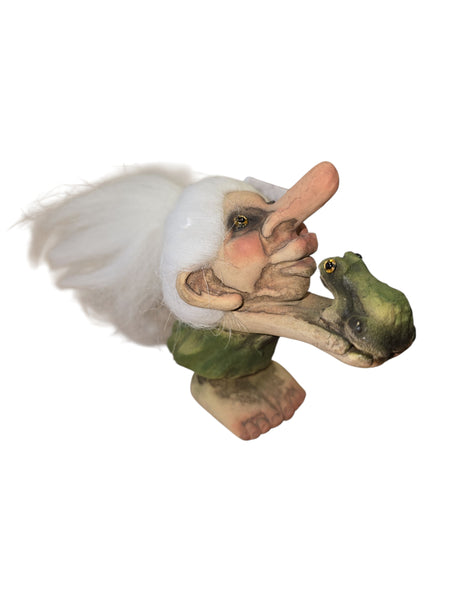 A small NyForm figurine—Girl Troll Kissing Frog—features a girl troll with white hair, exaggerated facial features, a green outfit, and a frog in her arms, showcasing charming Norwegian design.