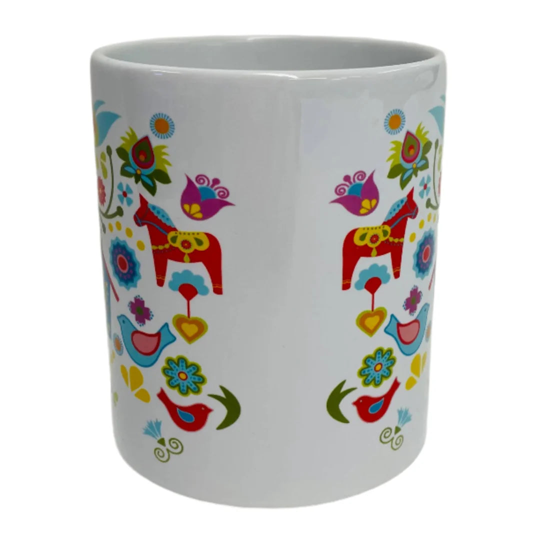 The Mug: Dala Horse with Bird House coffee mug 11 oz features vibrant Scandinavian folk art, decorated with Swedish Dala Horses, birds, flowers, and hearts in bold red, blue, yellow, and green on white ceramic.