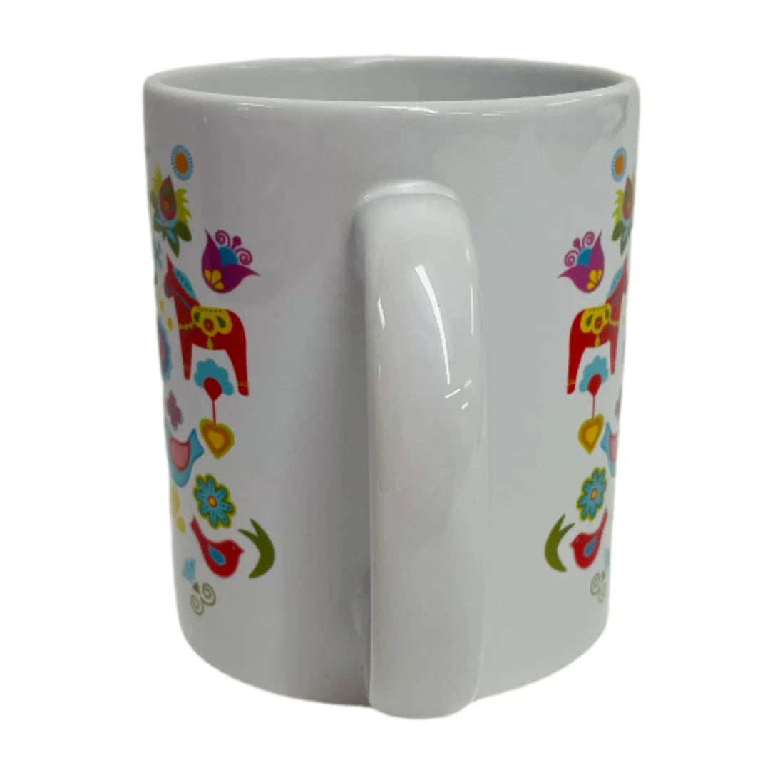 The Mug: Dala Horse with Bird House coffee mug is a white ceramic mug with a handle, showcasing vibrant floral and bird patterns alongside charming Swedish Dala Horses—perfect for fans of Scandinavian design.