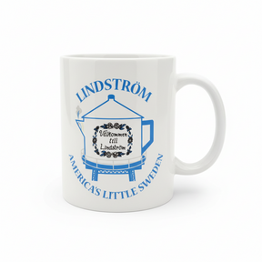 White 11oz mug featuring blue text and a coffee pot water tower illustration. Text reads: "Lindström, America’s Little Sweden" and "Välkommen till Lindström." A great Swedish heritage gift or Chisago Lakes souvenir.