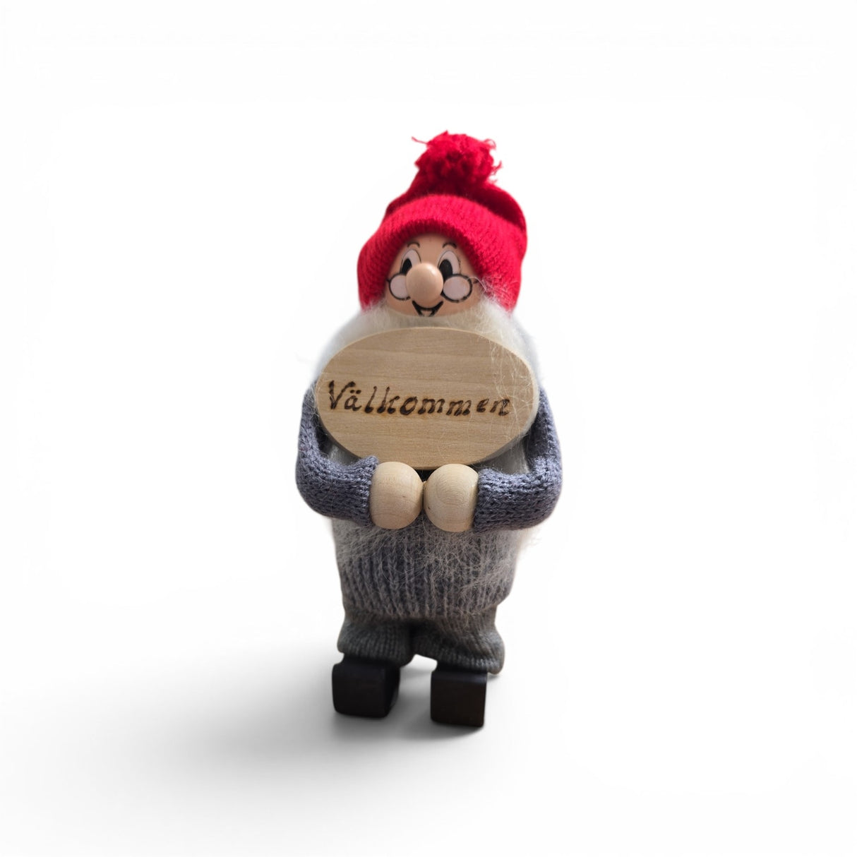 The Swallings 6.5" Swedish Santa figurine, handcrafted in Sweden, features a red cap, glasses, gray outfit, and holds a "Valkommen" sign—perfect Nordic holiday décor against any backdrop.
