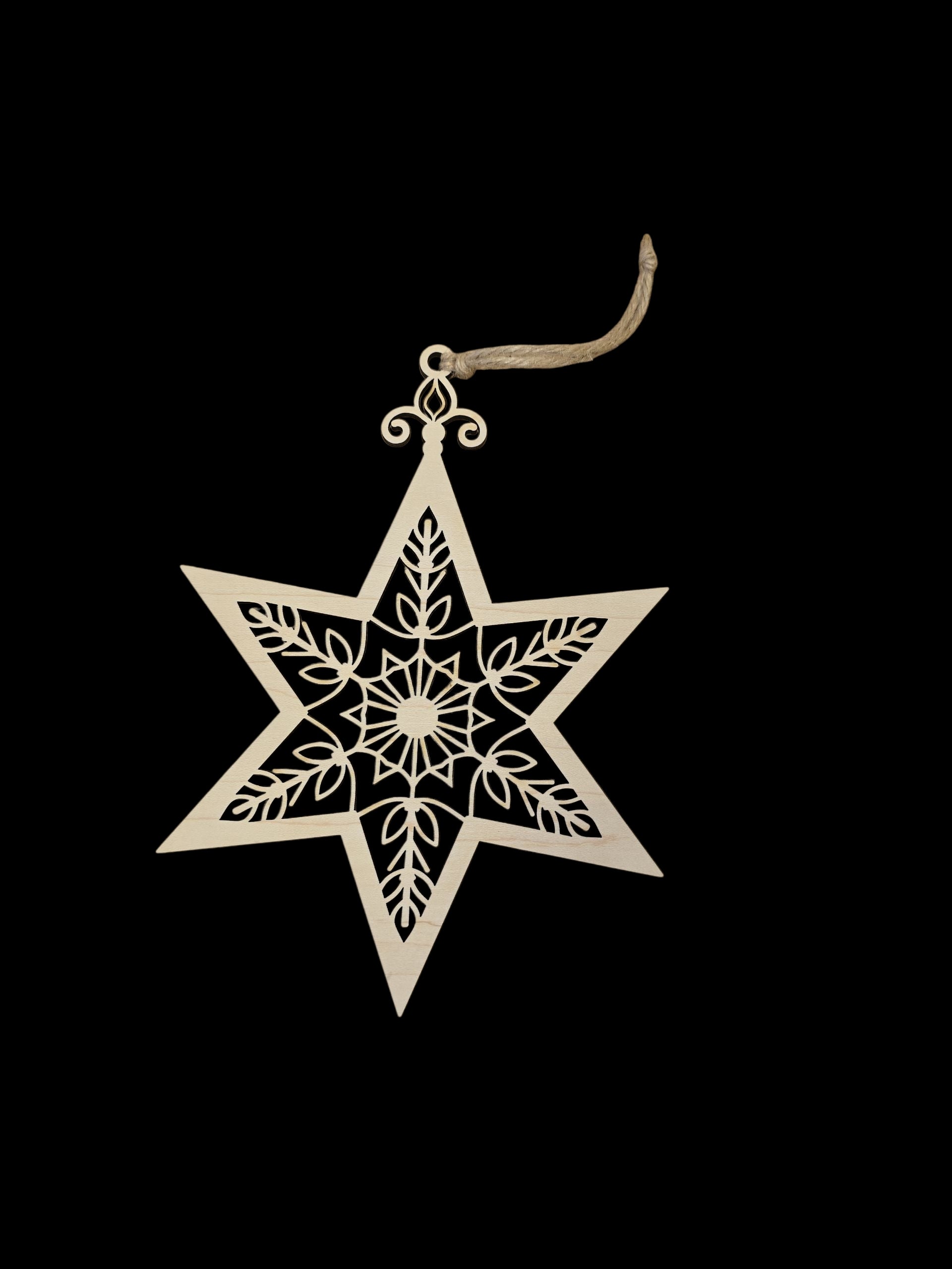 The Ornament: Laser Cut Star is an 8" high x 6" wide birch wood Christmas tree ornament with detailed cut-out patterns and a string loop for hanging, shown against a black background.