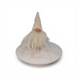 The "Foot Tomte" gnome figurine by Talla Imports, handcrafted by Gumselids of Sweden, features a tall white hat, long white beard, clay nose and feet, and sits on a round white platform against a plain white background.