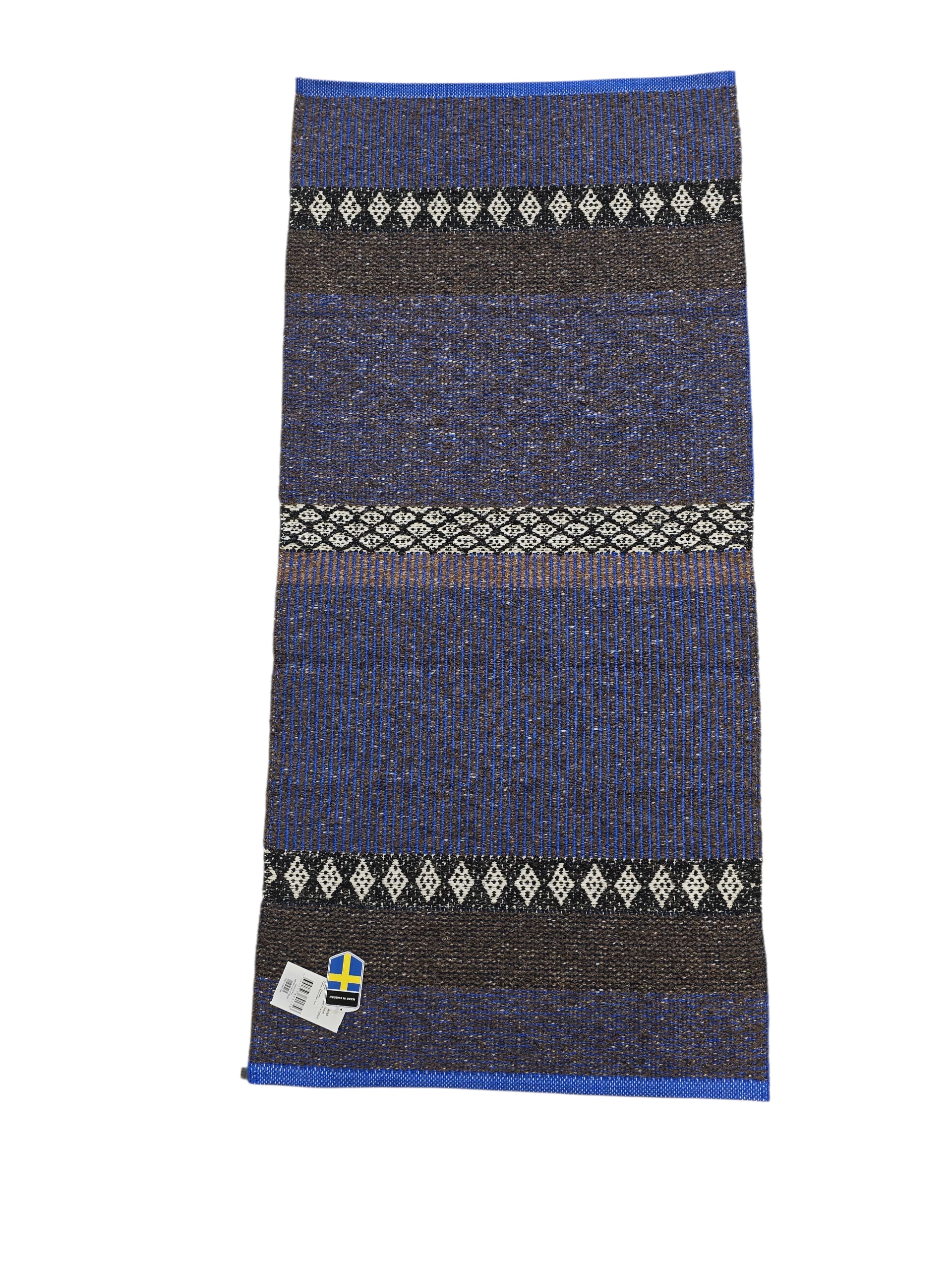 The Cotton/Vinyl Rug: Horredsmattan - Mixed Forest - Cobalt features blue, black, and white stripes with diamond patterns, shown flat with a Swedish flag label in the bottom left corner.