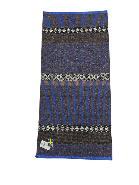 The Cotton/Vinyl Rug: Horredsmattan - Mixed Forest - Cobalt features blue, black, and white stripes with diamond patterns, shown flat with a Swedish flag label in the bottom left corner.