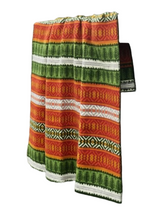 The Mora Blanket by Kerstin Landström is a folded Scandinavian throw made from 100% Norwegian lamb's wool, featuring horizontal stripes in red, green, white, and yellow with geometric and tree-like patterns.