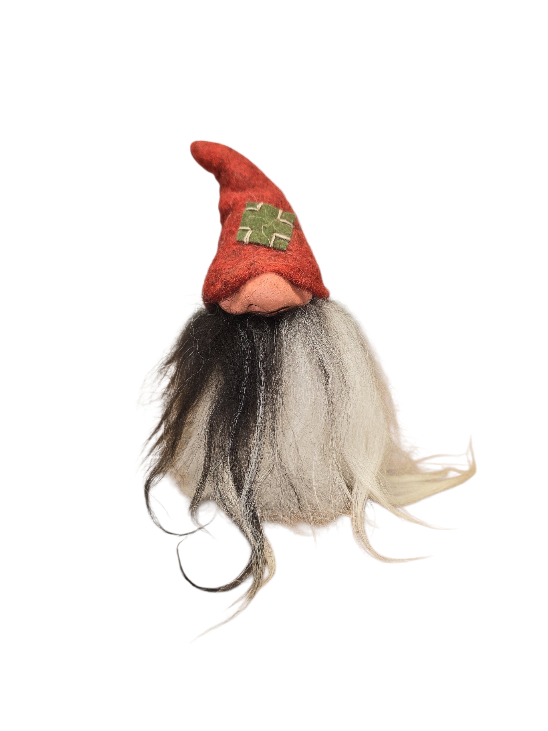 The "Patch Tomte" Gnome by Gumselids of Sweden is a 7" handcrafted figurine with a long white and black beard, large nose, and a red hat with a green cross, inspired by Swedish Tomte traditions, displayed on a wood base.