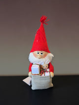 Nordic gnome figurine wearing a red pointed hat and holding a fabric sack filled with small gifts and a miniature toy rabbit.