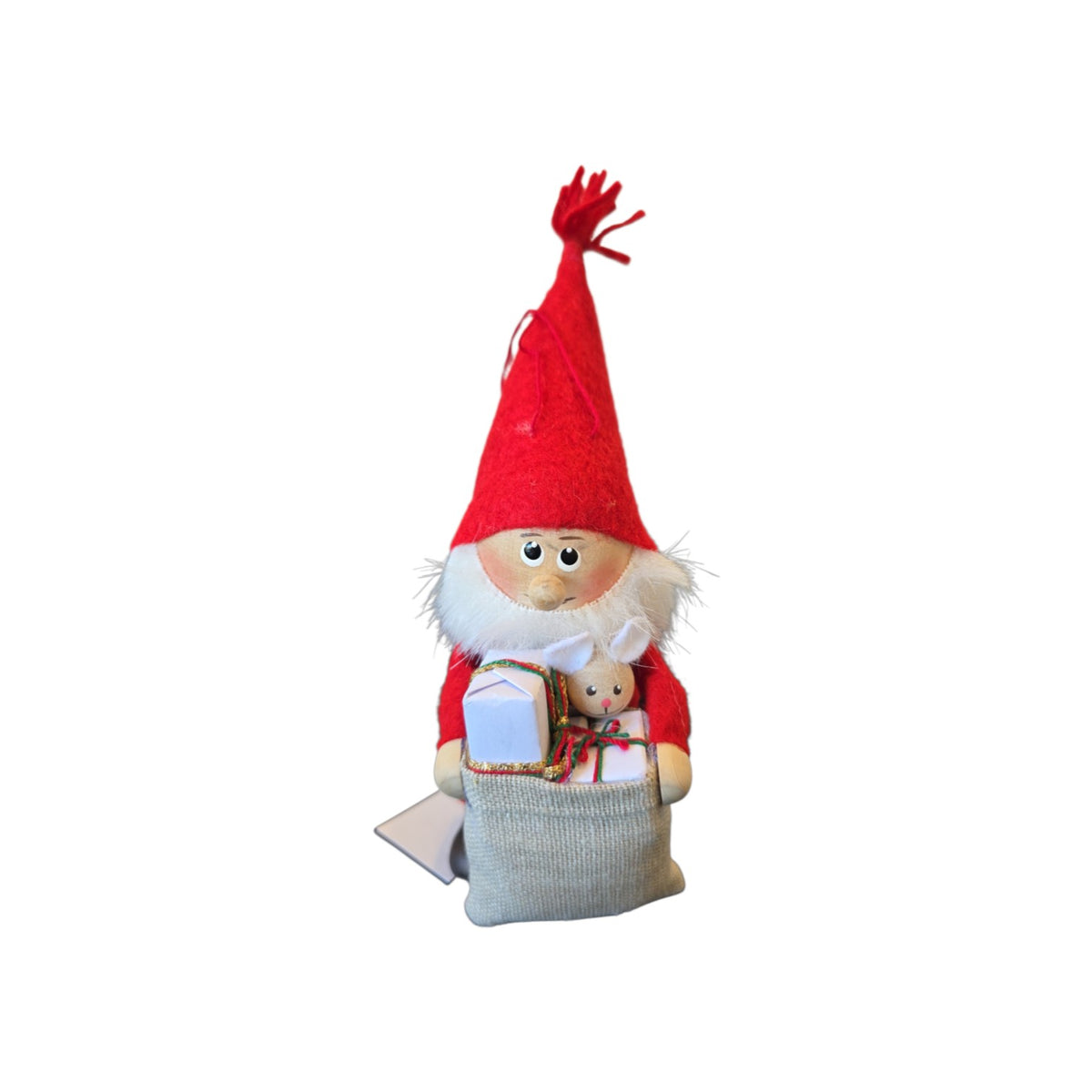 Scandinavian Santa figurine wearing a red hat, holding a sack with small wrapped gifts and a miniature toy rabbit.