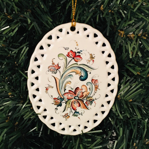 Introducing the 4" ceramic ornament by Lise Lorentzen, featuring a delicate floral design in the Creme Rosemaling style and an intricate lace edge. This ornament is perfect for adding a touch of traditional elegance to your Christmas tree.