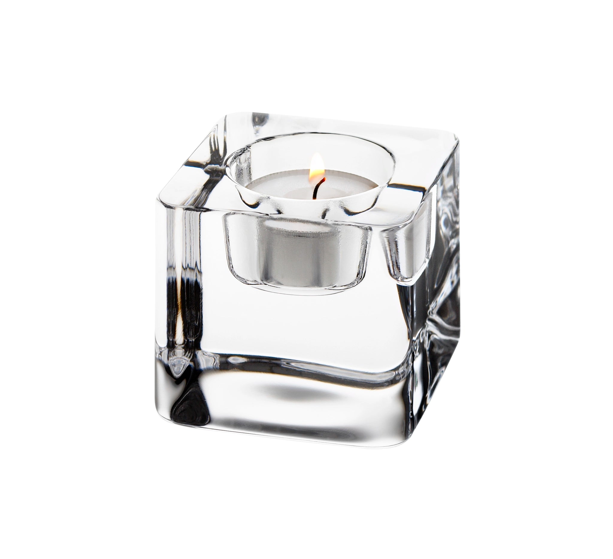 The Orrefors Ice Cube Votive Candle Holder, made of crystal, elegantly cradles a lit tealight candle on a white background.