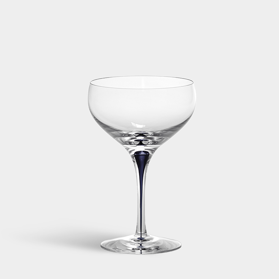 A clear, empty Orrefors Intermezzo Blue Coupe glass with a tall stem stands elegantly on a white background, its crystal construction reflecting refined craftsmanship.