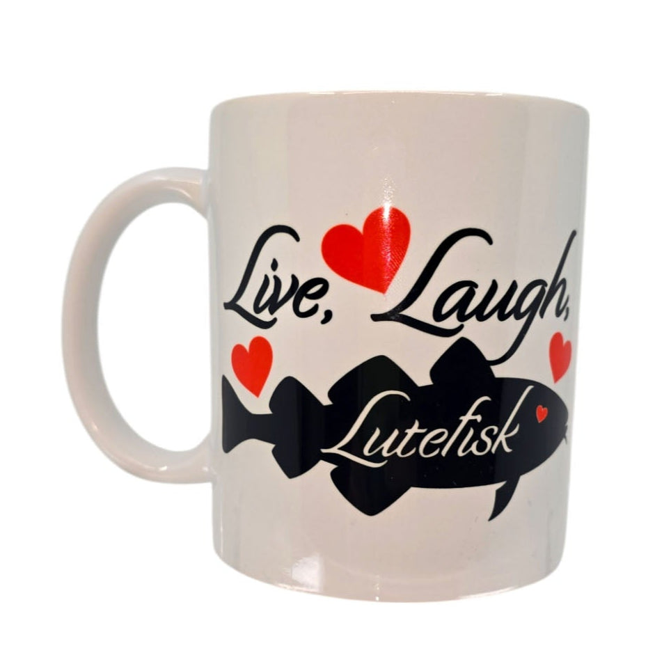 The Live Laugh Lutefisk white ceramic mug features Live, Laugh, Lutefisk in bold black text with red hearts and a whimsical black fish graphic. Its an ideal gift for those who love a playful nod to Swedish traditions.