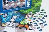 A colorful jigsaw puzzle with cartoon characters; some pieces are missing, exposing part of a man’s face dissolving into scattered puzzle pieces on a white background.