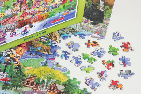 Partially completed jigsaw puzzle of Minnesota with scattered pieces nearby; puzzle box labeled “Minnesota Spirit” visible in the top left corner.