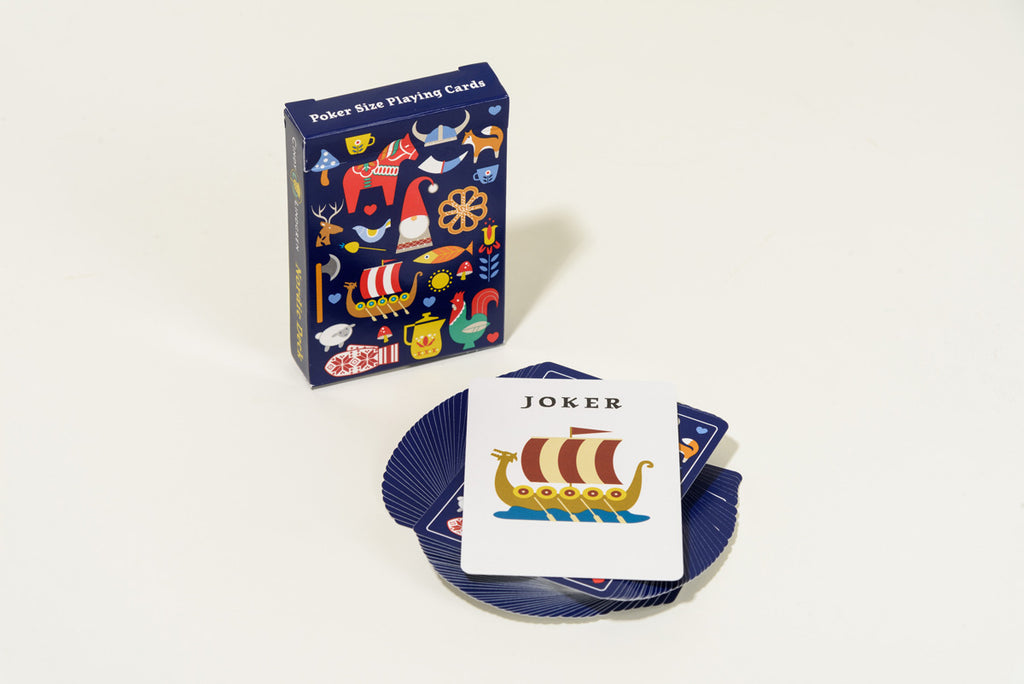 A Poker Size Nordic Deck of playing cards, featuring Scandinavian flair, is spread out. The top card displays a Joker with a vivid Viking ship design. The box is filled with colorful icons that celebrate the rich artistic tradition of the region.
